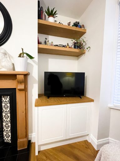 Corner living room setup with a television on a wooden stand and shelves above.